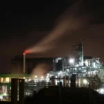 guerra en Medio Oriente petróleo, refinería de petróleo iluminada de noche representando la crisis energética y el alza de precios por el conflicto en Medio Oriente 2026.