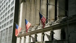 Fragilidad en el sistema bancario en 2026 representada por la fachada de la Bolsa de Nueva York con banderas de Estados Unidos