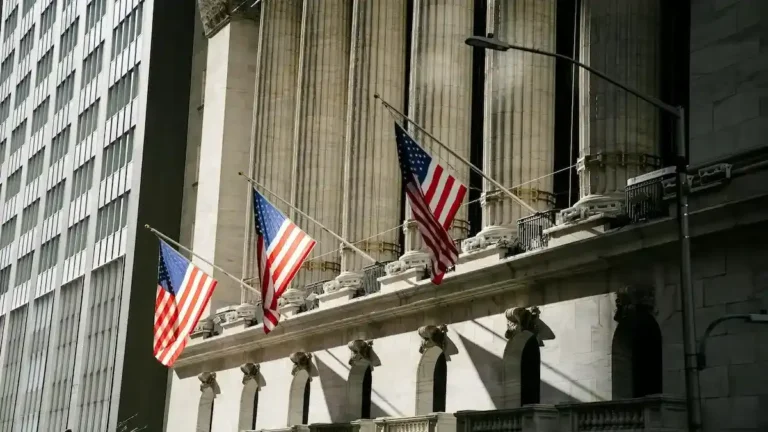 Fragilidad en el sistema bancario en 2026 representada por la fachada de la Bolsa de Nueva York con banderas de Estados Unidos