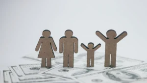 Figuras de madera que representan una familia sobre billetes de dólar para aprender a crear un presupuesto familiar desde cero.