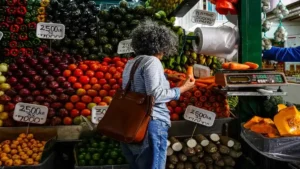 Mujer comprando vegetales en un mercado de alimentos para analizar el impacto de la inflación en el costo de vida actual.