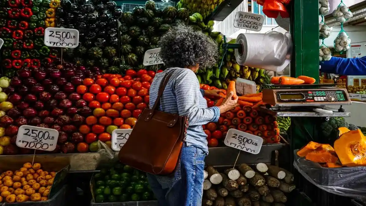 Mujer comprando vegetales en un mercado de alimentos para analizar el impacto de la inflación en el costo de vida actual.